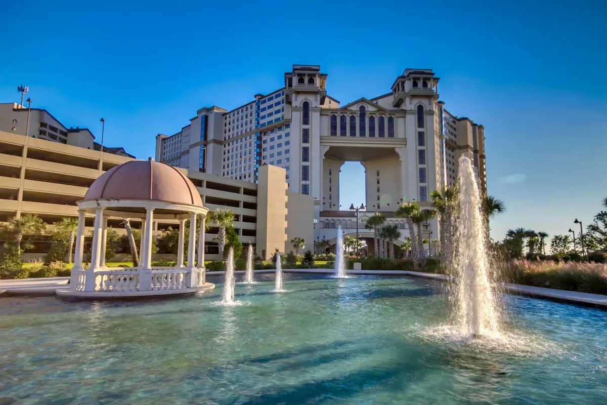 A serene exterior courtyard featuring a charming gazebo surrounded by fountains and elegant architectural details. The setting is bathed in warm, inviting sunset light, suggesting a tranquil spot for gathering with friends or enjoying relaxing moments outdoors.